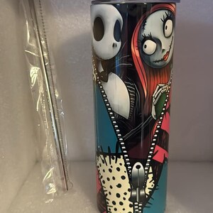 May include: A stainless steel tumbler with a colorful design featuring Jack Skellington and Sally from The Nightmare Before Christmas. The design includes a zipper and polka dots.