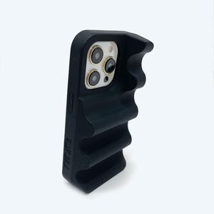 以下が含まれることがあります： テクスチャ加工されたグリップと隆起したカメラバンプを備えた黒い電話ケース。ケースの側面には「PIZZI」という文字が印刷されています。