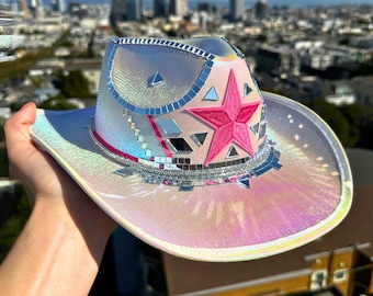 May include: A white iridescent cowboy hat with a pink star and silver mirrored accents.