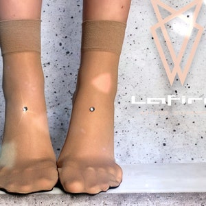 Peut inclure: Une paire de chaussettes transparentes couleur chair avec un petit strass sur chaque cheville.