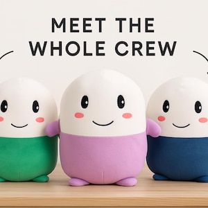 May include: Three plush, egg-shaped toys with smiling faces and small arms. Each has a white top and a coloured bottom: green, purple, and navy blue. The text "MEET THE WHOLE CREW" is above them.