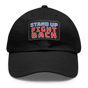 May include: Black baseball cap with a white patch that says "STAND UP FIGHT BACK" in red, blue, and white letters.