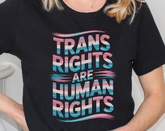 May include: Black t-shirt with the text "Trans Rights Are Human Rights" in colourful stylized lettering. The lettering is in a rainbow colour scheme.
