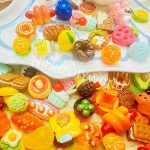 May include: A collection of colorful miniature food charms, including donuts, cupcakes, sandwiches, fruit, and pastries. The charms are made of polymer clay and are perfect for adding a touch of whimsy to crafts and projects.