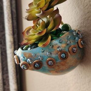 Hanging gourd pot decorated with teal blue glass beads and wooden rings.