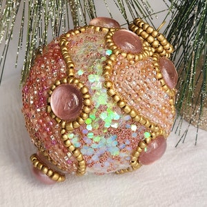 Christmas ornament decorated with pink sequins, and pink and golden glass beads.