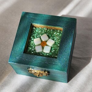 Small, beaded jewelry box painted in jade green, its lid is decorated with white and green glass beads representing a little flower.
