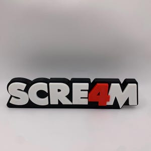 Könnte beinhalten: Ein schwarz-weißes 3D-gedrucktes Schild mit der Aufschrift "SCREAM4", wobei die Zahl 4 rot ist.
