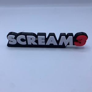 Könnte beinhalten: Ein schwarz-weißes 3D-gedrucktes Schild mit der Aufschrift "SCREAMS" und einer roten 3.