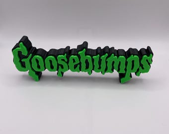 May include: A 3D printed Goosebumps logo in black and green. The logo is in a stylised font with a dripping effect.