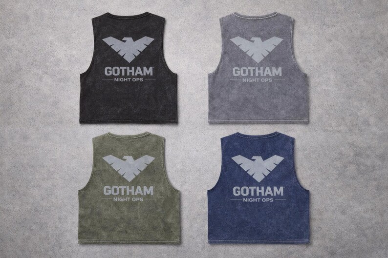 May include: Four sleeveless tank tops in black, gray, olive green, and navy blue. Each tank top features a gray bat symbol and the text "GOTHAM NIGHT OPS" printed on the back. The tops have a vintage, washed appearance.