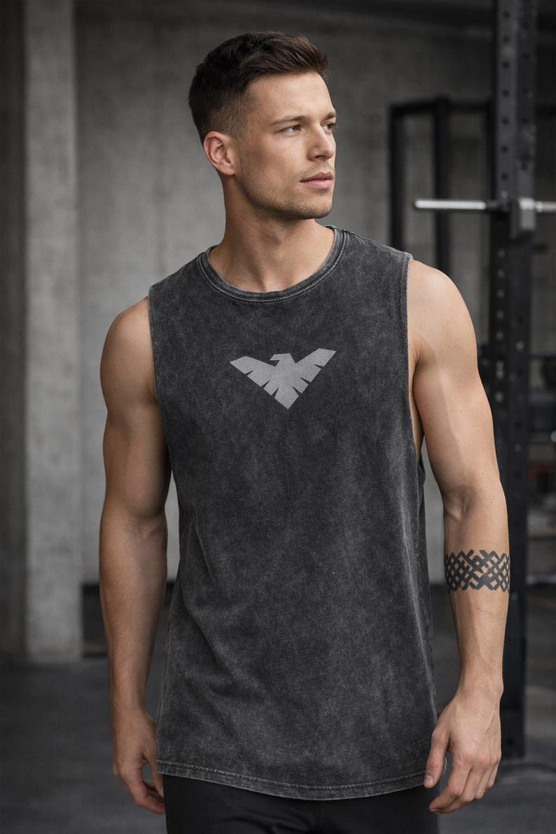 May include: Dark gray sleeveless workout shirt with a faded texture and a gray eagle logo on the chest. The shirt is made of a soft material and is suitable for gym or casual wear.
