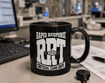 May include: A black ceramic mug featuring white text that reads RAPID RESPONSE RRT NURSE CRITICAL CARE DEPT. The mug has a handle on the right side and contains a hot liquid with visible steam rising from the top, set against a blurred office background.