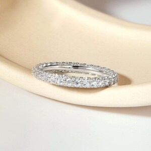 May include: A silver band ring with a double row of small, clear cubic zirconia stones.