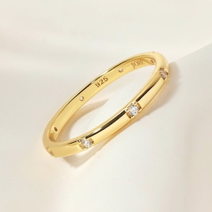 May include: A gold band ring with small clear stones set around the band. The ring is marked "925" on the inside.