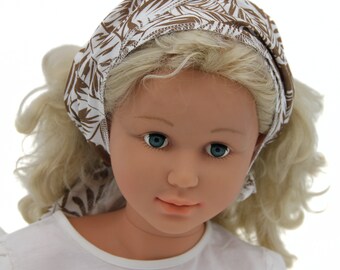 Diadema para atar confeccionada en muselina orgánica con motivo de hojas de palma en color beige sobre fondo blanco.