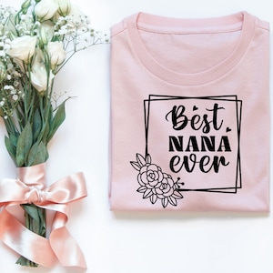 May include: A pink t-shirt with a black graphic that says "Best Nana Ever" in a decorative frame with a floral design.