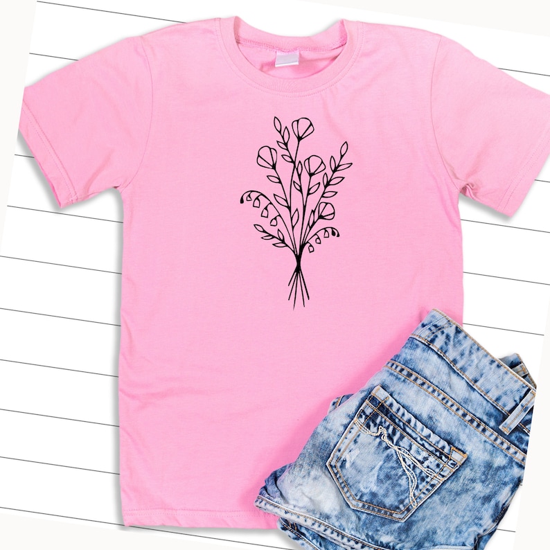 May include: A pink t-shirt with a black line drawing of a bouquet of flowers on the front.