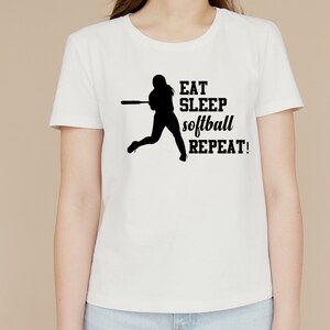 May include: White t-shirt with a black silhouette of a softball player and the text "EAT SLEEP softball REPEAT!"