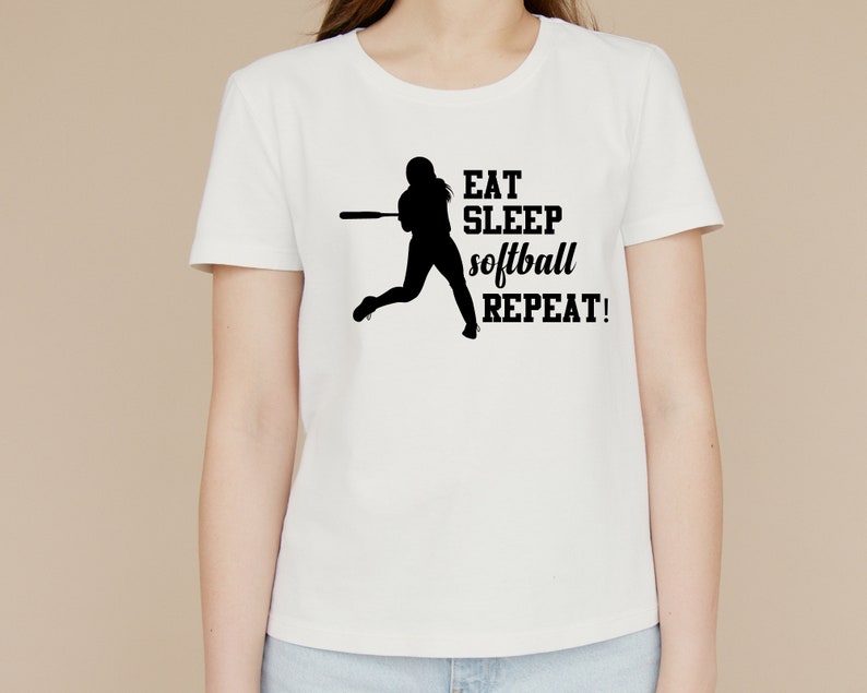 May include: White t-shirt with a black silhouette of a softball player and the text "EAT SLEEP softball REPEAT!"
