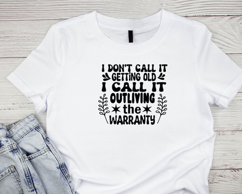 May include: White t-shirt with black text that reads "I don't call it getting old I call it outliving the warranty".