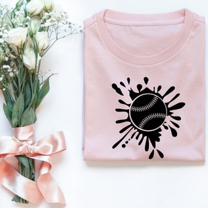 May include: A pink t-shirt with a black baseball graphic and a splatter design.