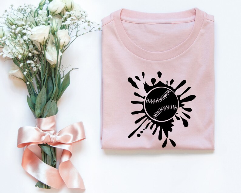 May include: A pink t-shirt with a black baseball graphic and a splatter design.