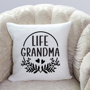 May include: White throw pillow with black text that reads "Life Grandma" in a circle with two small hearts and leafy branches.