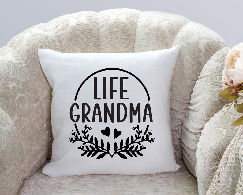 May include: White throw pillow with black text that reads "Life Grandma" in a circle with two small hearts and leafy branches.