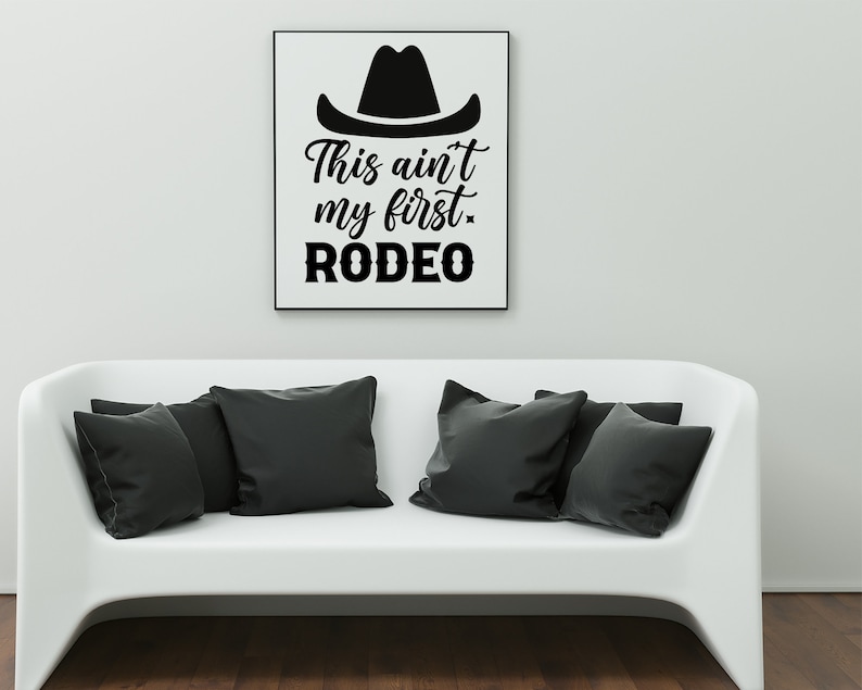 以下が含まれることがあります： カウボーイハットと「This ain't my first rodeo」というテキストが書かれた白黒のグラフィックプリントです。