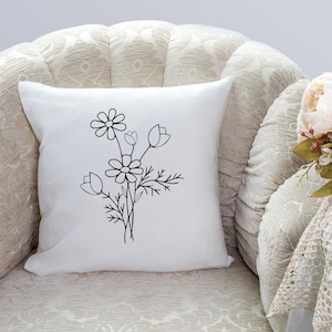 May include: A white throw pillow with a black line drawing of a bouquet of flowers. The flowers are stylized and include daisies and tulips.