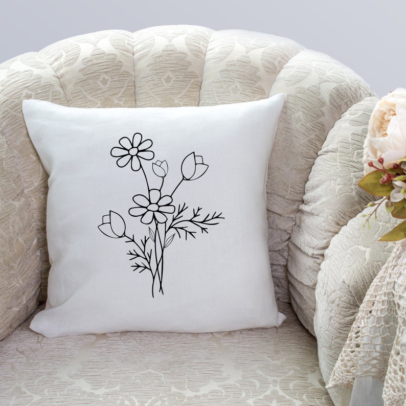 May include: A white throw pillow with a black line drawing of a bouquet of flowers. The flowers are stylized and include daisies and tulips.