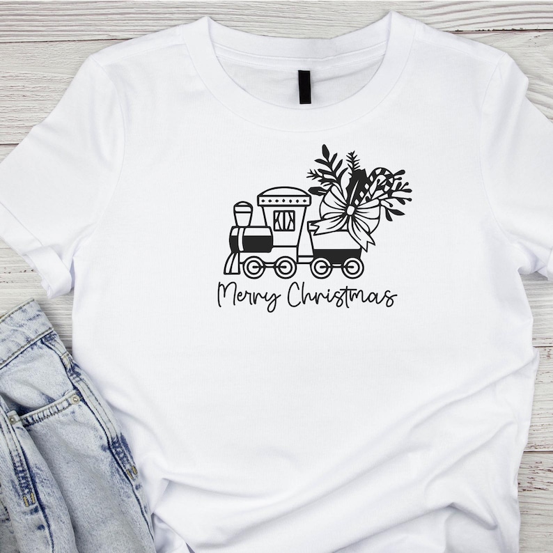 May include: White t-shirt with a black and white graphic of a toy train with a Christmas tree and bow on top. The text "Merry Christmas" is below the train.