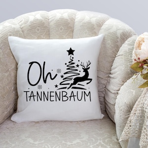 May include: White throw pillow with black text and a graphic of a Christmas tree and a deer. The text reads "Oh Tannenbaum".