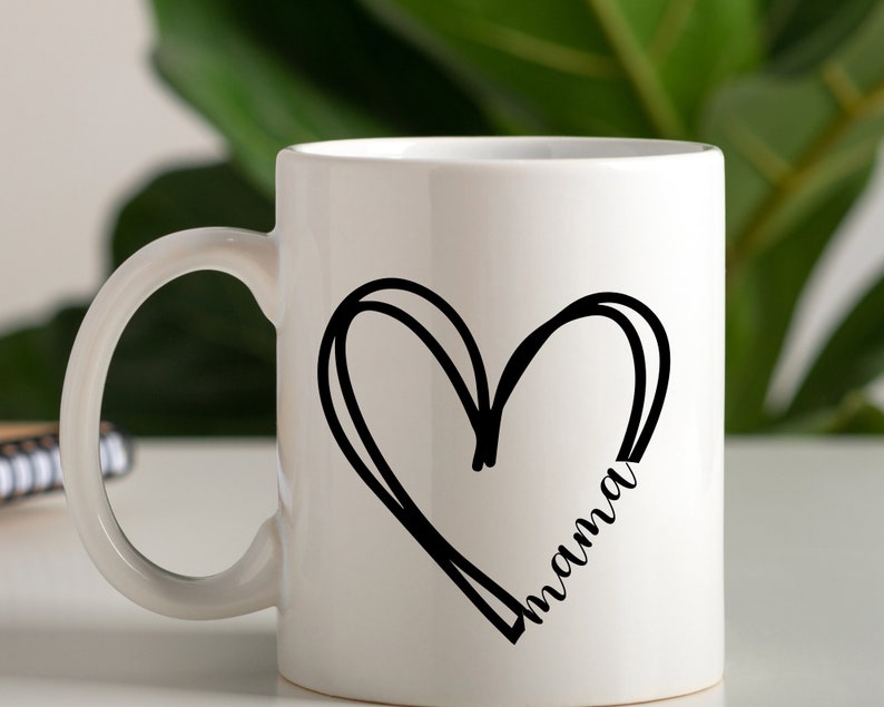 May include: White ceramic mug with a black hand-drawn heart design and the word "mama" inside the heart.