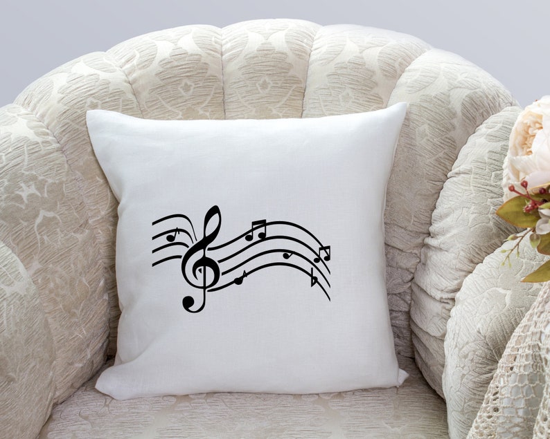 May include: White throw pillow with a black musical note design. The design features a treble clef and musical notes on a wavy line.