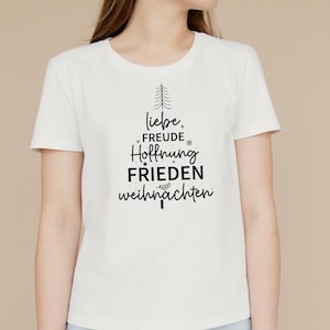 May include: White t-shirt with a black Christmas tree design. The tree is made up of the words "liebe", "freude", "hoffnung", "frieden", and "weihnachten".