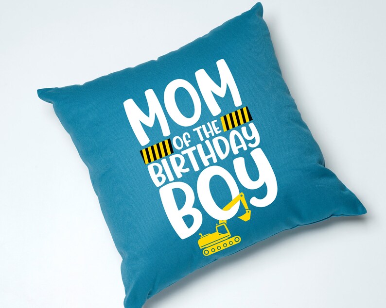 May include: Blue throw pillow with white text that reads "Mom of the Birthday Boy" with a yellow and black striped design and a yellow excavator graphic.