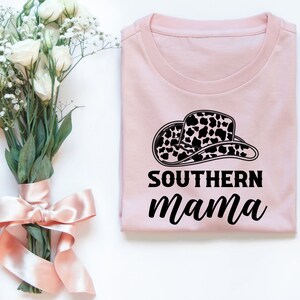 以下が含まれることがあります： 黒と白の牛柄の帽子と「SOUTHERN mama」という黒い文字が書かれたピンクのTシャツです。