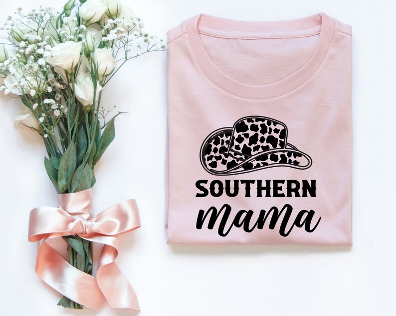以下が含まれることがあります： 黒と白の牛柄の帽子と「SOUTHERN mama」という黒い文字が書かれたピンクのTシャツです。