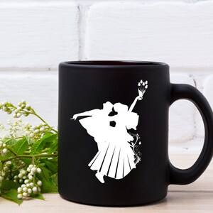 May include: Black ceramic mug with a white silhouette of a couple dancing. The woman is holding a bouquet of flowers.