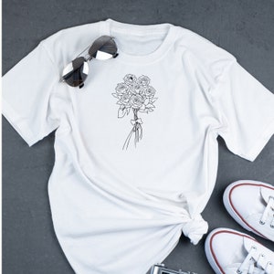 May include: White t-shirt with a black line drawing of a bouquet of roses.