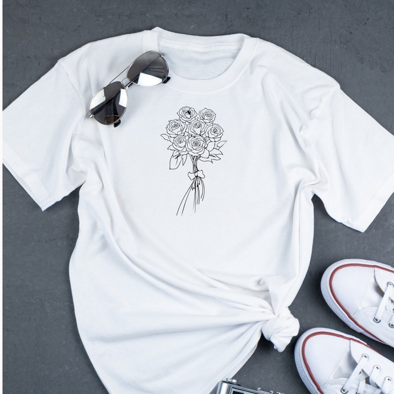 May include: White t-shirt with a black line drawing of a bouquet of roses.