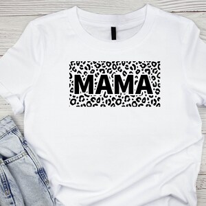 May include: White t-shirt with a black leopard print design and the word "MAMA" in black text.