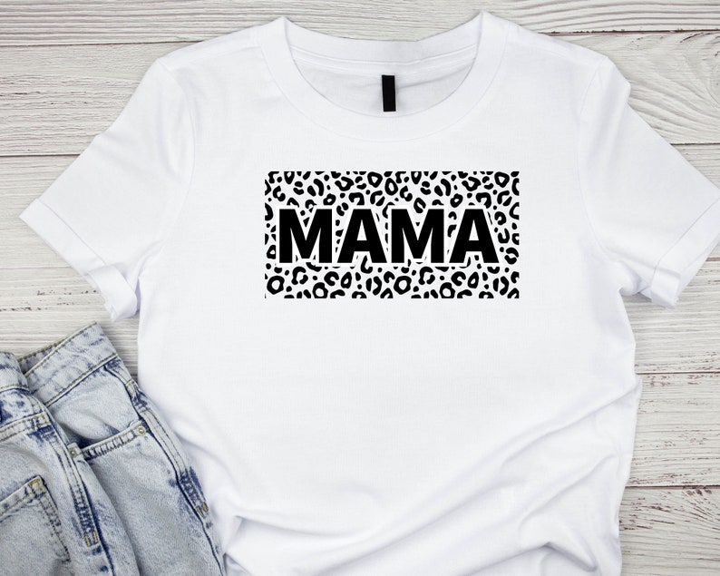 May include: White t-shirt with a black leopard print design and the word "MAMA" in black text.