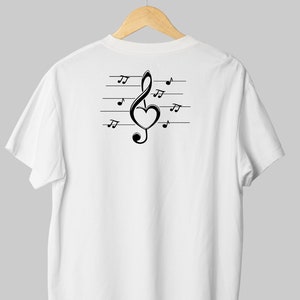 May include: White t-shirt with a black treble clef design featuring a heart in the middle of the clef. The clef is on a staff with musical notes.