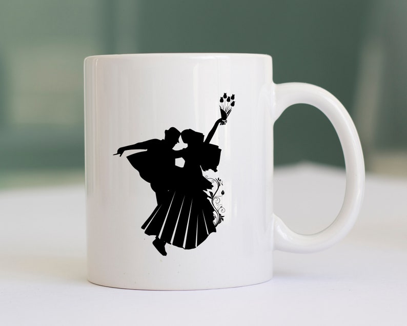 May include: White ceramic mug with a black silhouette of a couple dancing. The woman is holding a bouquet of flowers.
