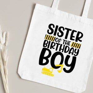 May include: White tote bag with black text that reads "Sister of the Birthday Boy" with yellow and black construction stripes and a small yellow construction vehicle graphic.