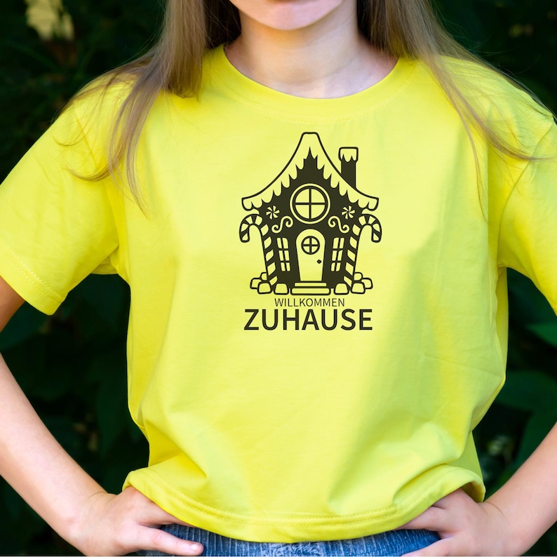 May include: A yellow t-shirt with a black gingerbread house graphic and the text "Willkommen Zuhause".