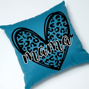 May include: A teal blue cushion with a black heart-shaped design featuring a leopard print pattern. The word "mama" is written in a black cursive font inside the heart.